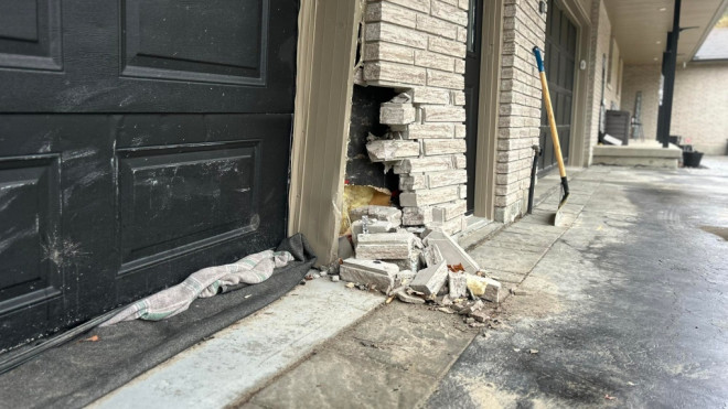 The brick wall and garage door is damaged after the crash. (CTV News/Heather Senoran)