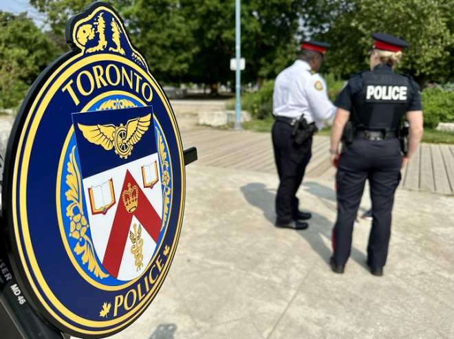 Toronto Police Service officers speak with a resident after a news conference.