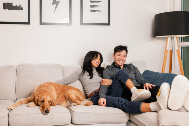 Ginette Nguyen and Michael Nguyen on their couch with their golden retriever