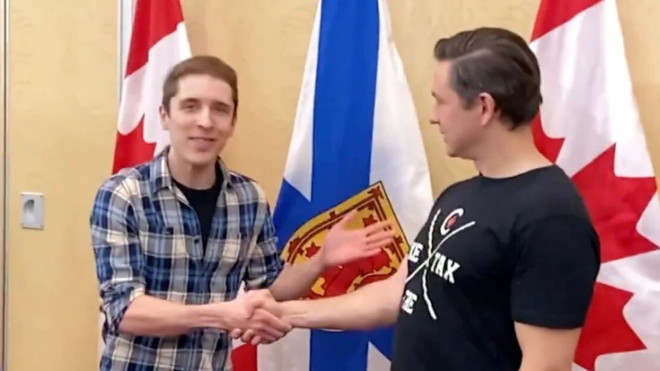 Two men shaking hands with the flags of Canada and Nova Scotia behind them.