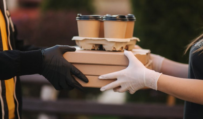 Man from food delivery service bring pizza and coffee. Hands in protective mask.