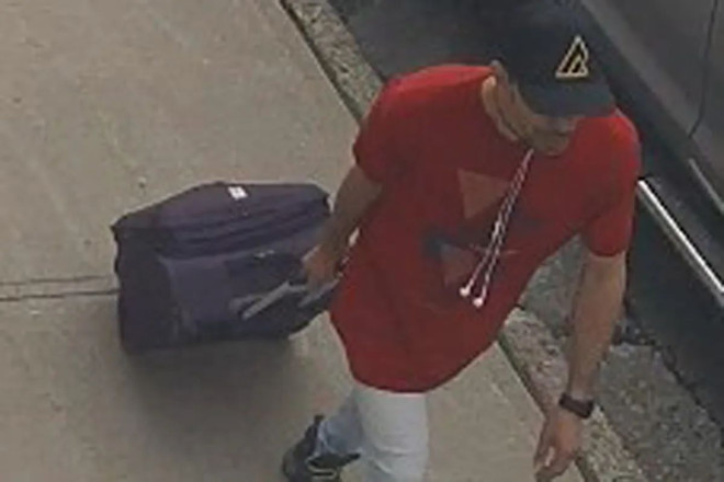 A surveillance image of a man with a suitcase.