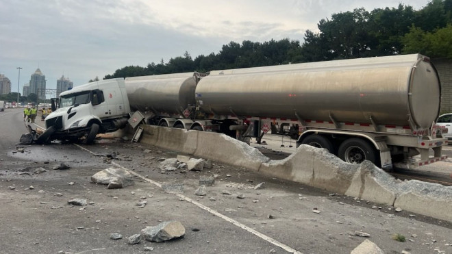 A tractor-trailer is seen straddling the median between the eastbound express and collector lanes of Highway 401