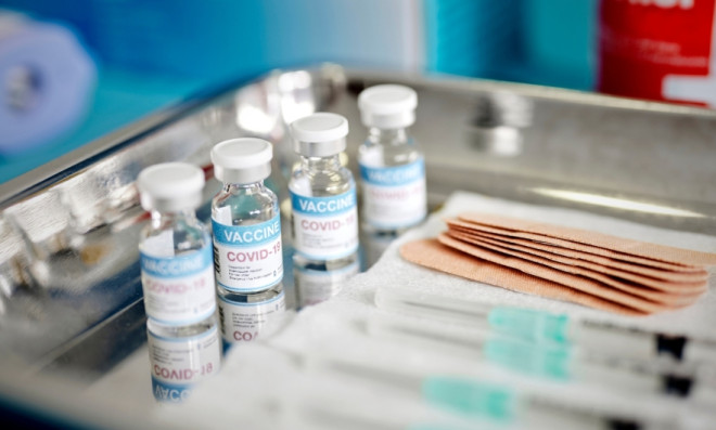 covid vaccine vials, syringes, and bandaids on a metal tray