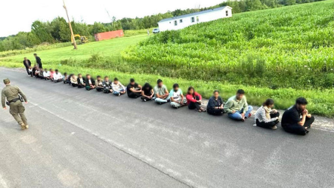 U.S. Border Patrol officers detain a large group of people after crossing into an area near Champlain, N.Y., in July. (U.S. Border Patrol)
