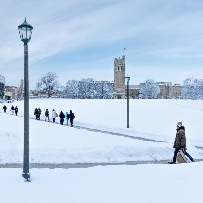 University College hill shot from the bottom of the hill shows the hill covered in a fresh layer of snow. People in winter gear walk on the sidewalks up the hill.