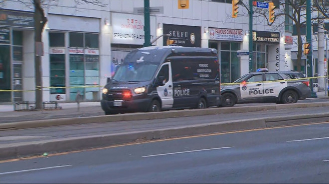 Police vehicles are pictured at the scene of a shooting near Spadina Avenue and Queen Street West in downtown Toronto Saturday December 7, 2024. 