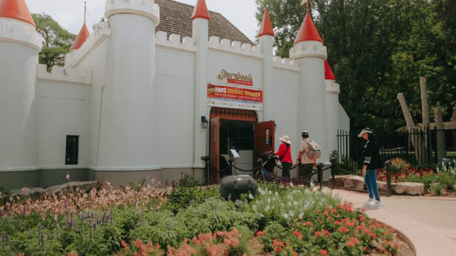 A family enters the Storybook Gardens white castle through the front gate.