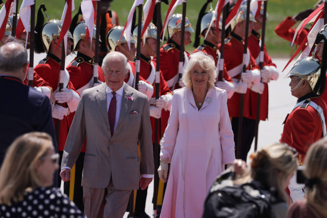 Their Majesties walking by a ceremonial guard.