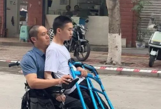 瘫痪父亲坐轮椅抱着先天小脑萎缩的儿子进考场