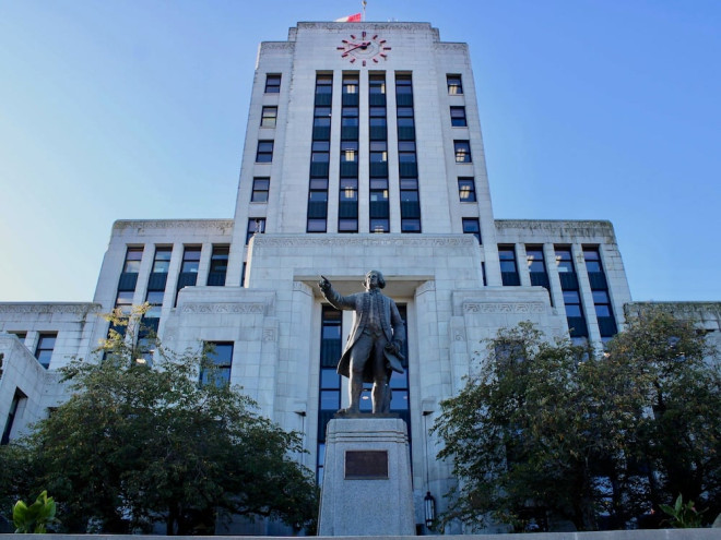A grey cement art deco building, Vancouver City Hall, on a sunny day in fall.