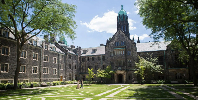 Historic stone building in Toronto with lush green trees and a manicured lawn, perfect for sightseeing and exploring Toronto’s architectural heritage.