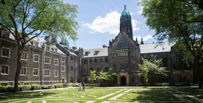Historic stone building in Toronto with lush green trees and a manicured lawn, perfect for sightseeing and exploring Toronto’s architectural heritage.