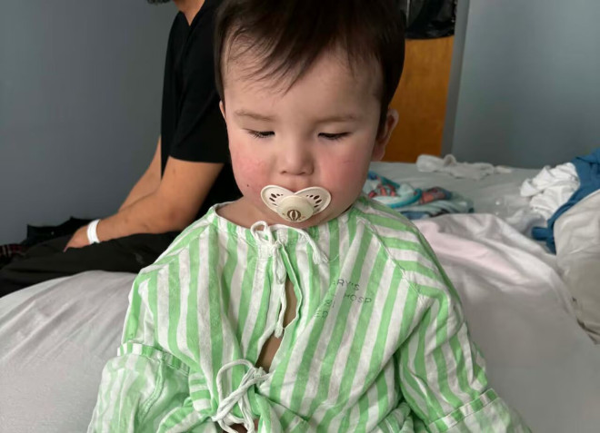 一个穿着绿色条纹病号服、坐在病床上的胖婴儿