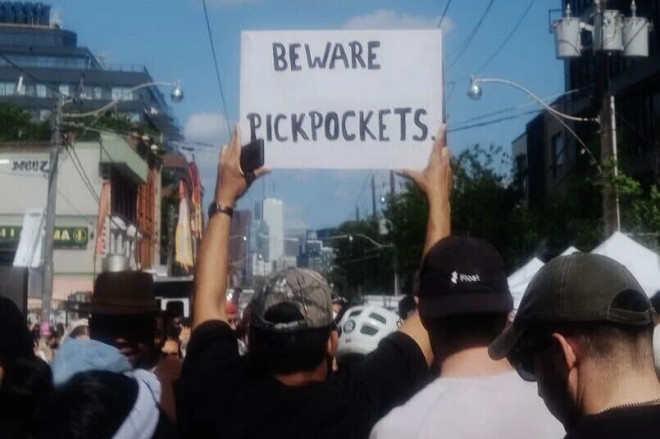 有警告扒手的标语被举在 Dundas West Fest 的人群上。