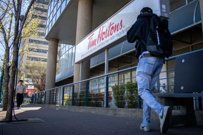 一名行人在埃德蒙顿的一家 Tim Hortons 门前经过。