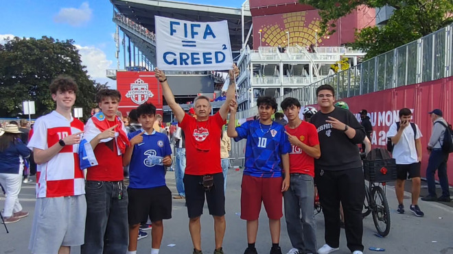 Jan Maracewicz 举着写有“FIFA = GREED”蓝字横幅，站在人群中央。