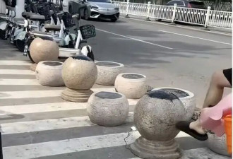 海水浴场门口隔离石墩被涂抹沥青 游客带娃被粘上
